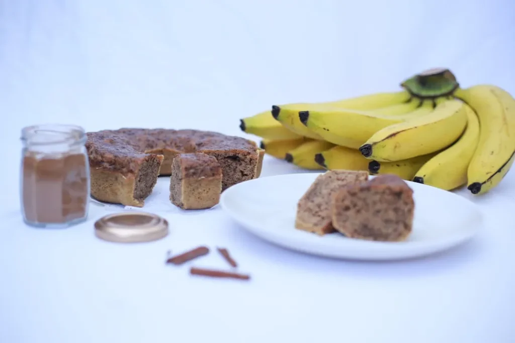 A white plate topped with slices of cake next to bananas