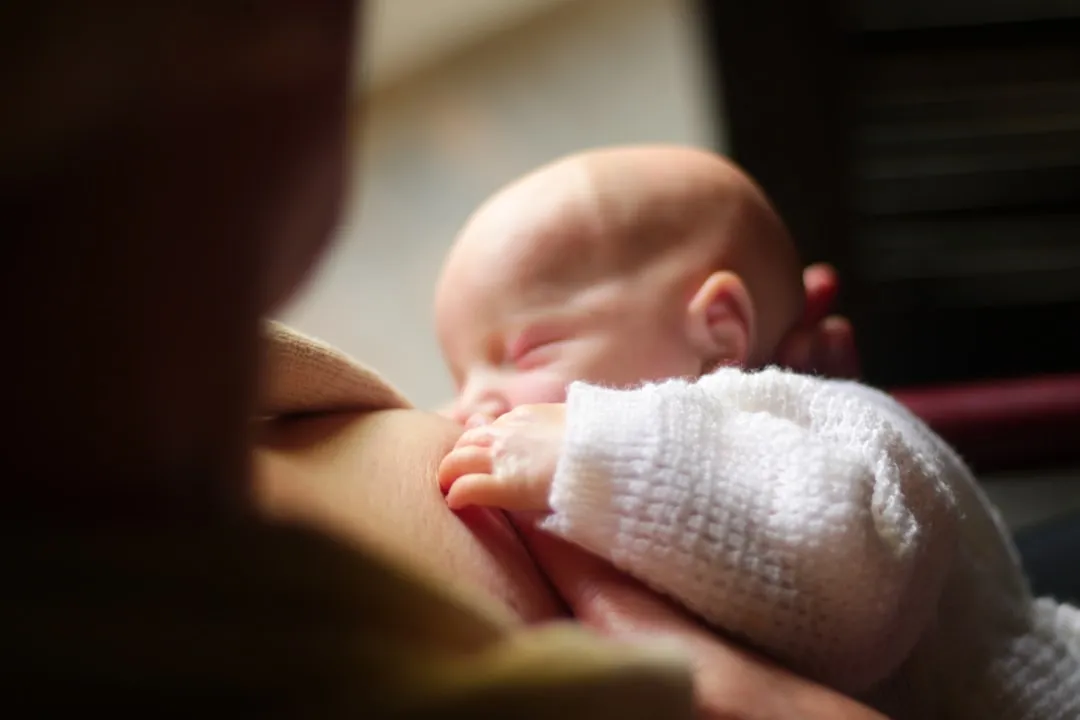 Mother is breastfeeding her sleeping baby.