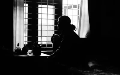 a black and white photo of a person sitting in front of a window