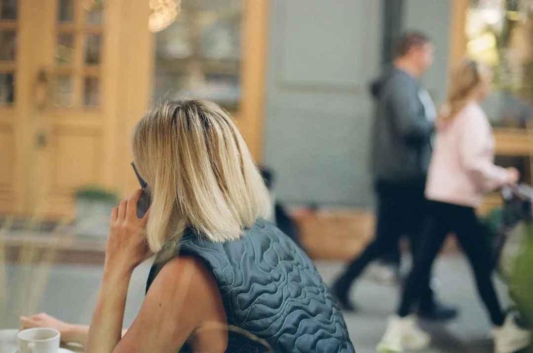 a woman sitting at a table talking on a cell phone