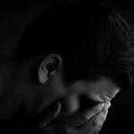 Man with head in hands in dark