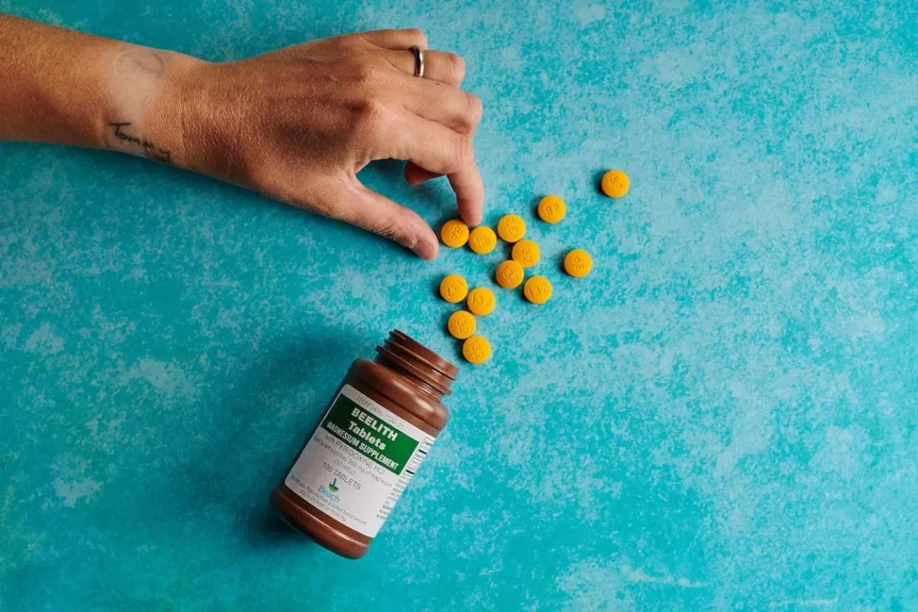 a hand reaching for a bottle of pills on a blue surface