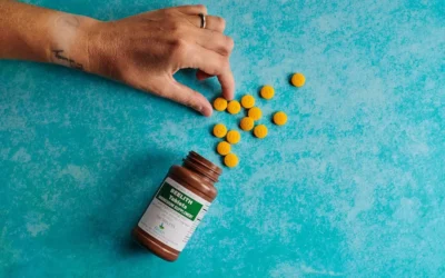 a hand reaching for a bottle of pills on a blue surface