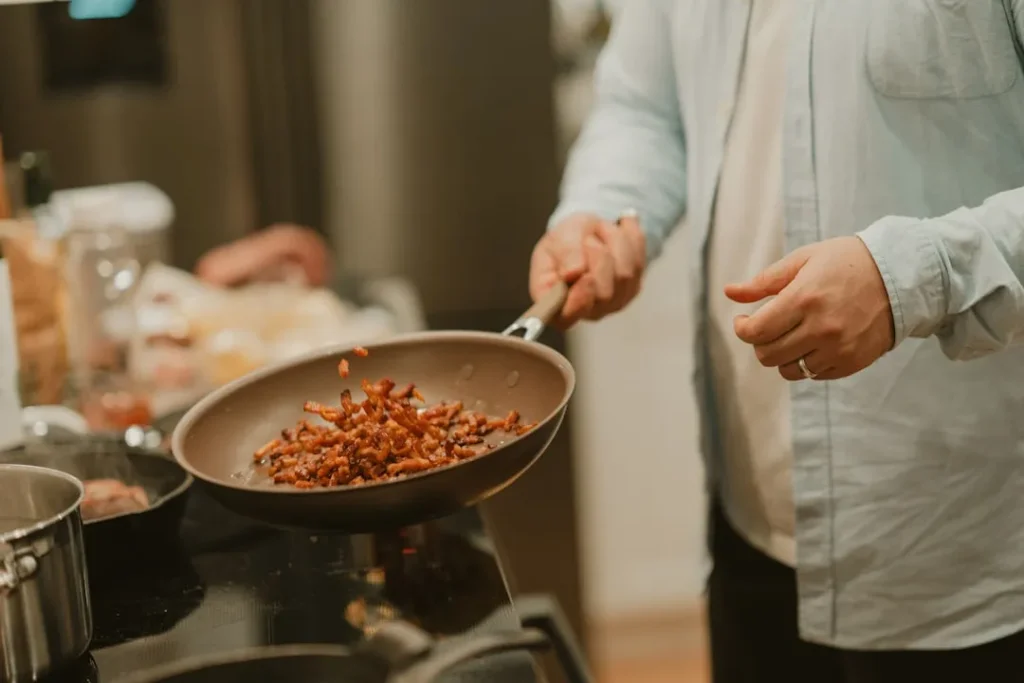 A woman cooking food in a frying pan on a stove