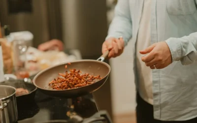 A woman cooking food in a frying pan on a stove