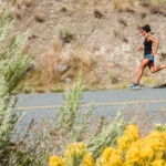 woman in black tank top running on gray asphalt road during daytime