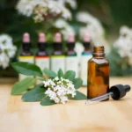 a bottle of essential oils sitting on a table next to a bunch of flowers