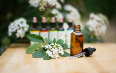 a bottle of essential oils sitting on a table next to a bunch of flowers