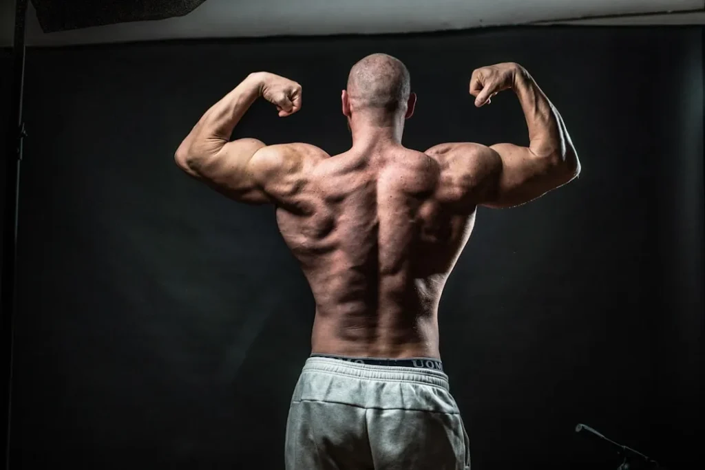 a man flexing his muscles in front of a black background