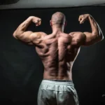 a man flexing his muscles in front of a black background