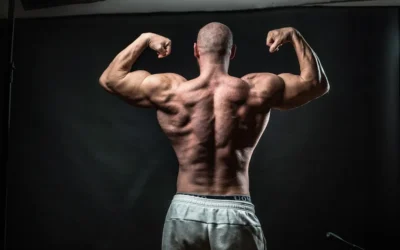 a man flexing his muscles in front of a black background