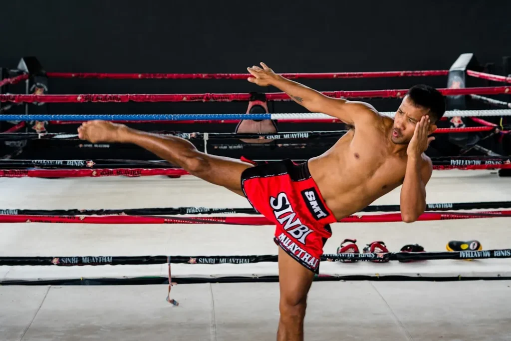 A shirtless man kicking a kick in a boxing ring