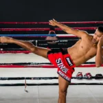 A shirtless man kicking a kick in a boxing ring