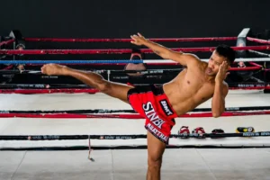 A shirtless man kicking a kick in a boxing ring