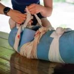 Applying a splint to an injured leg with bandages.