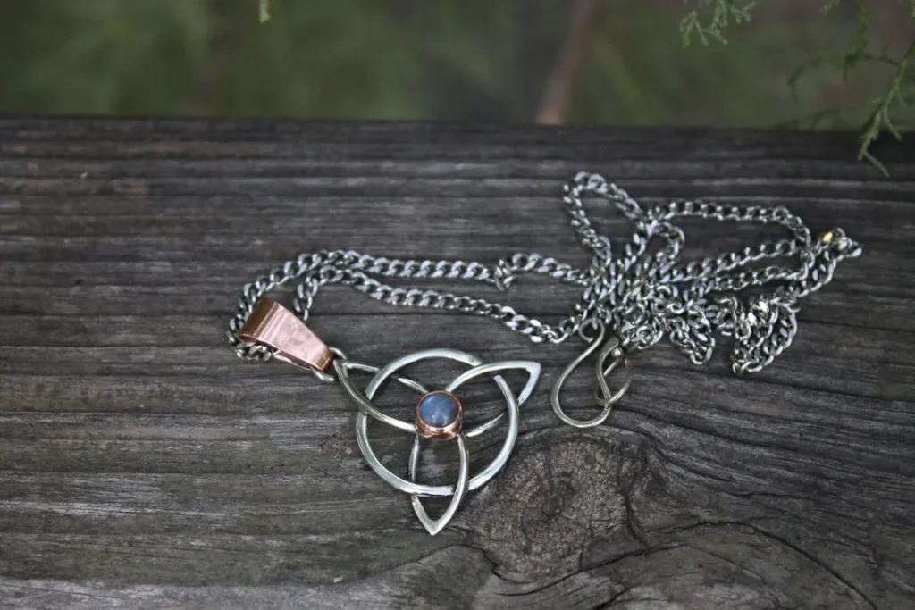 Celtic knot pendant with blue stone on wood