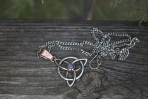 Celtic knot pendant with blue stone on wood